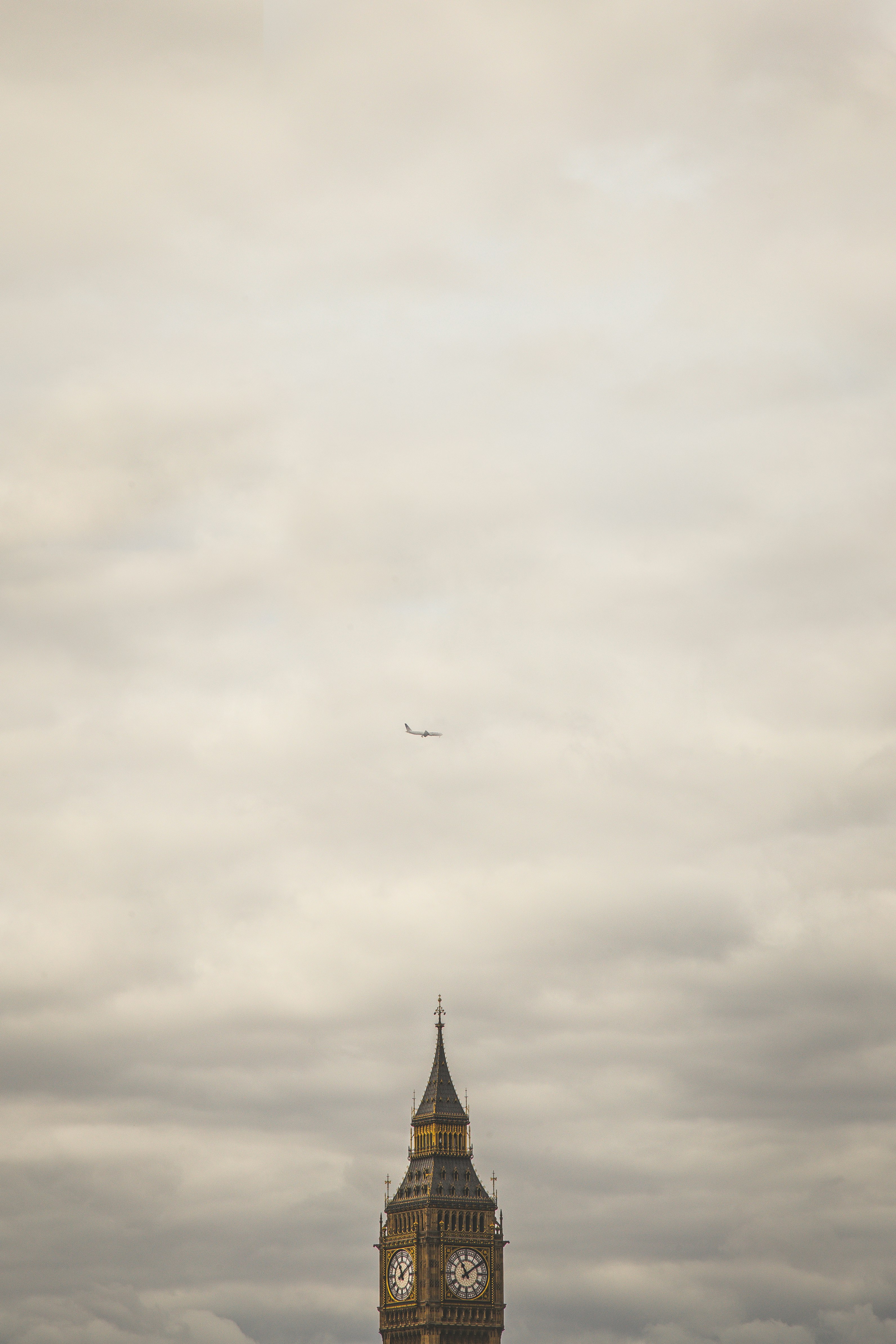 Elizabeth Tower under of white airliner during heavy clouds